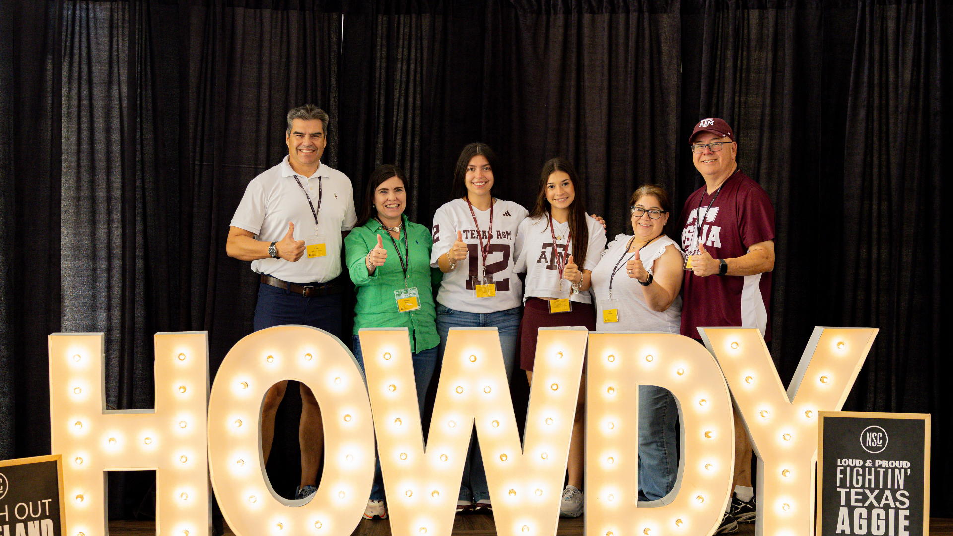 A family takes a photo with the Howdy sign during the New Student Conference.