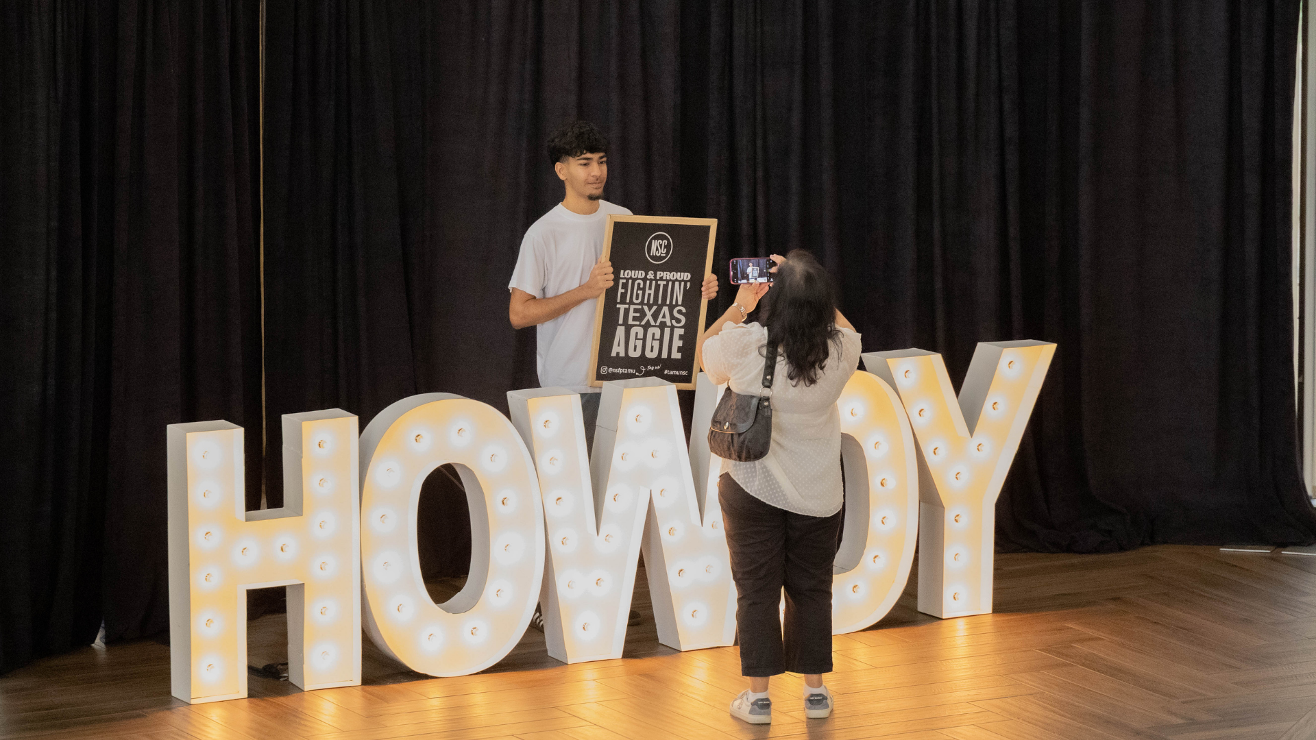 A student takes their photo with the Howdy sign during the New Student Conference.